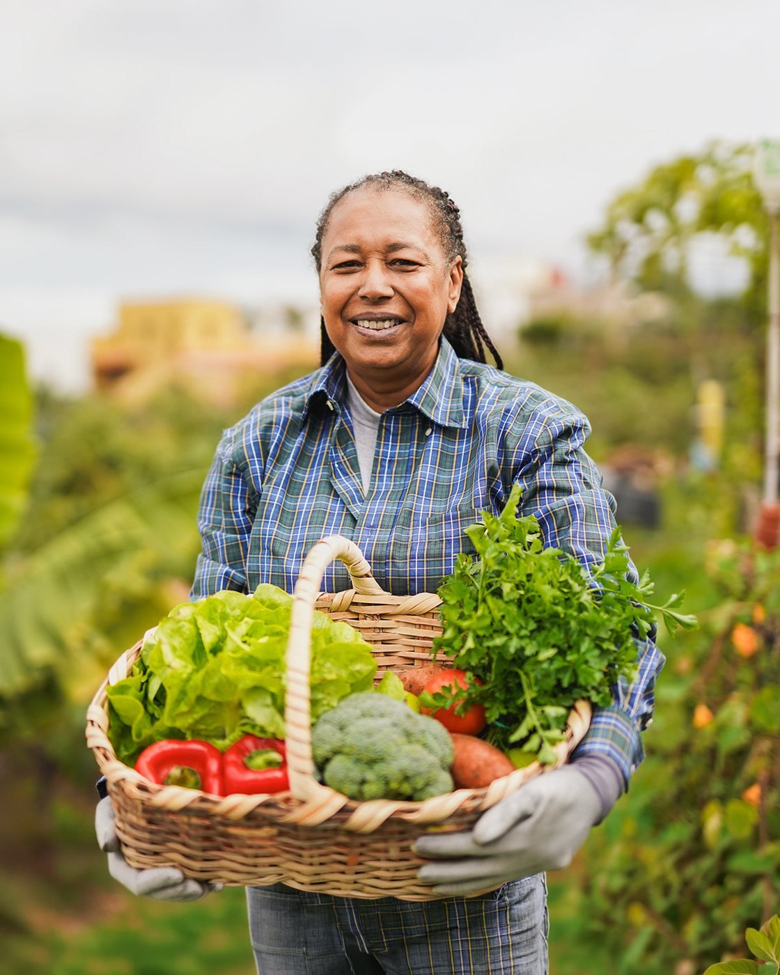 Woman holding a basket of fresh vegetables from her garden